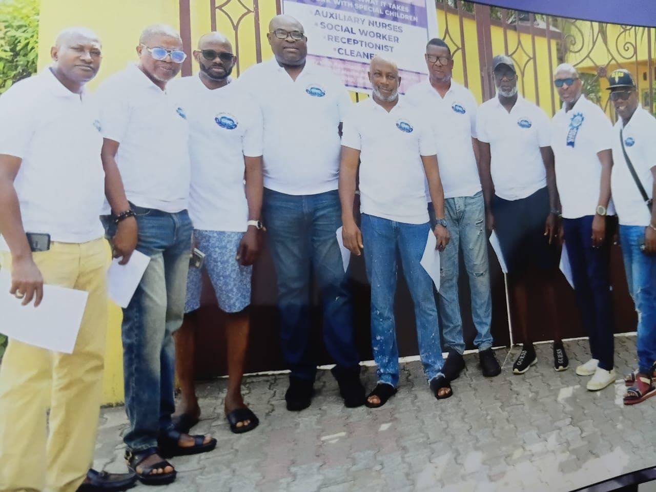 Club members in matching white polo shirts lined up outside a care centre during an outreach visit